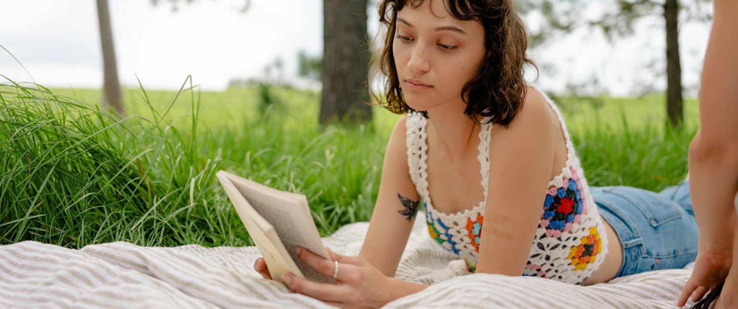 Auf dem Bild sieht man zwei Hände und ein offenes Heft. Die eine Hand hält einen Stift und beginnt, etwas in das Heft zu schreiben.